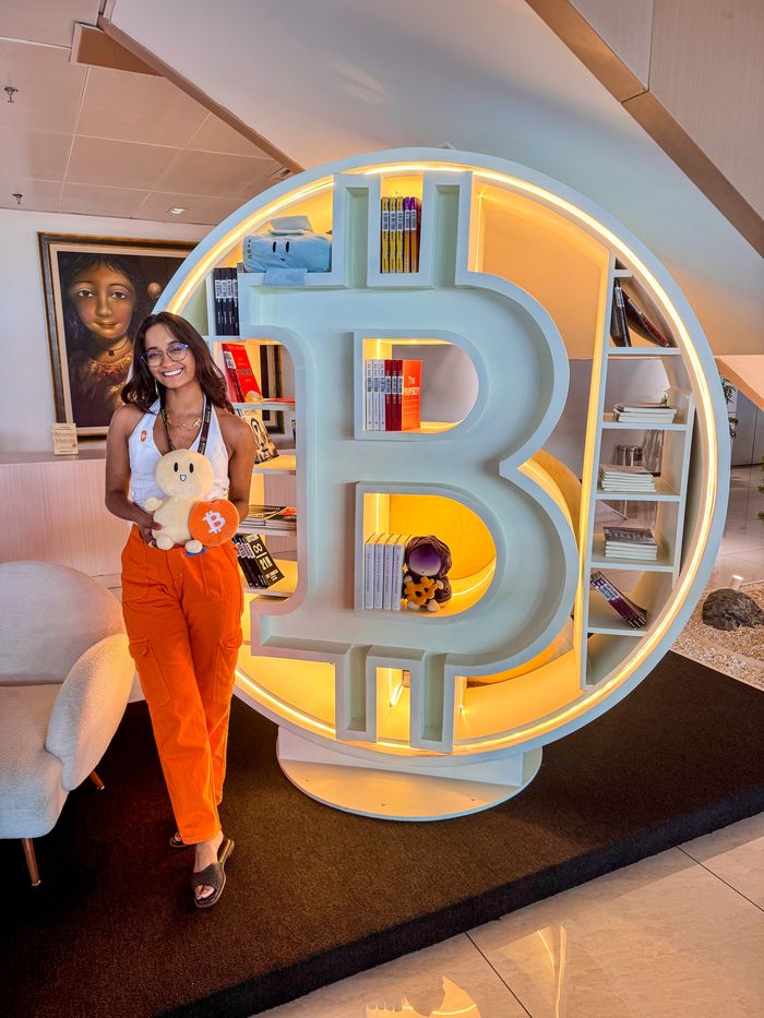 Pamela Posada junto a un letrero de Bitcoin